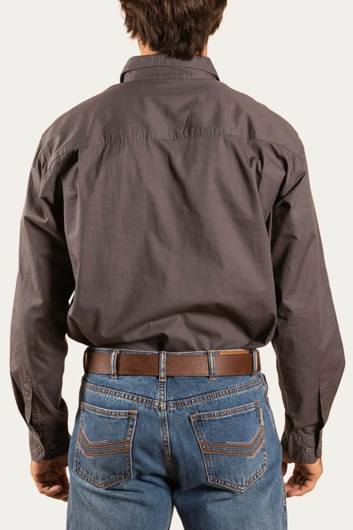 A person seen from behind wears a dark Ringers Western King River Half Button Shirt tucked into blue jeans with a brown belt, set against a plain light background.