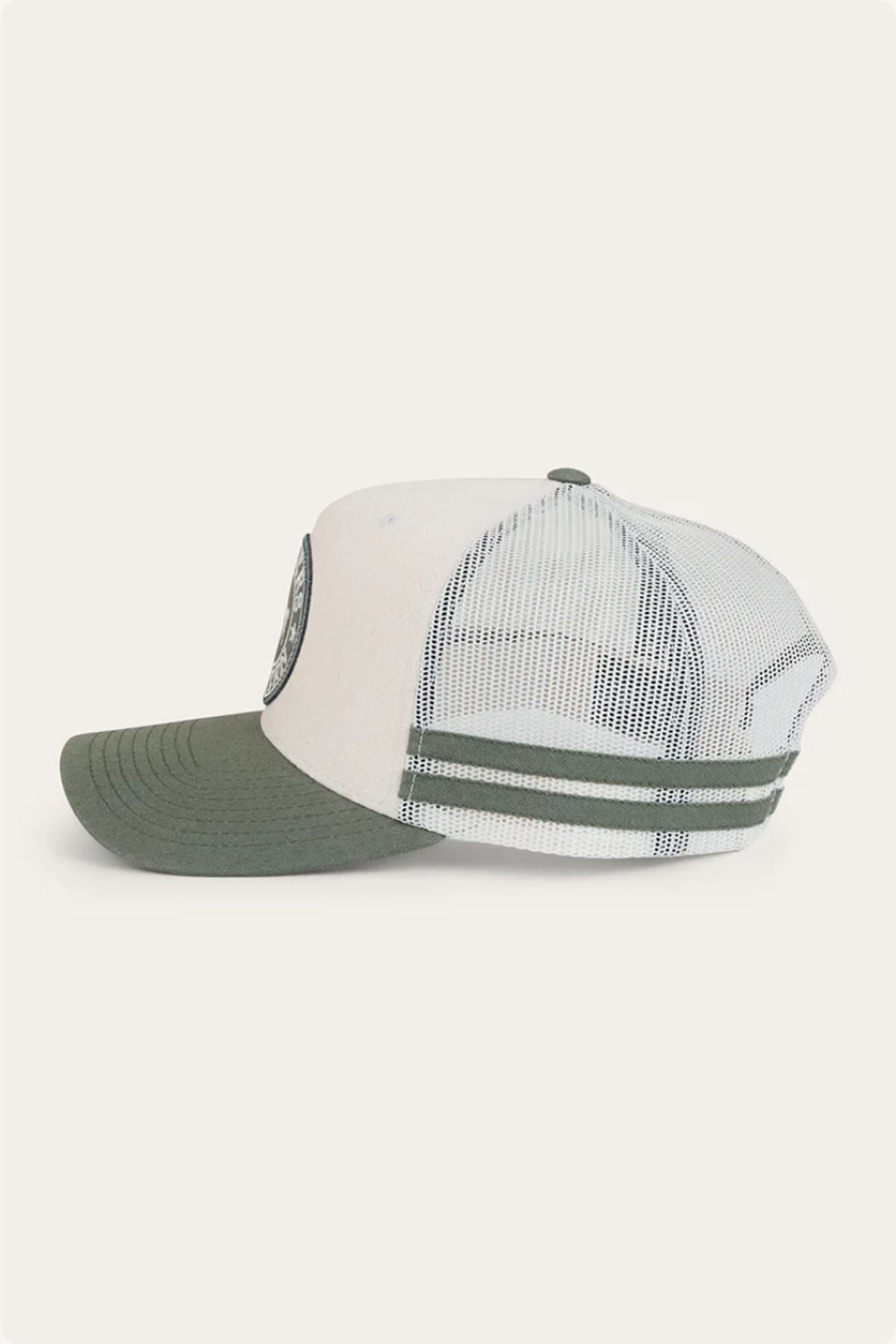 The Ringers Western McCoy Trucker Cap, with a white and green design, cotton twill front, mesh back, and curved green brim, is displayed from the side against a plain light background.