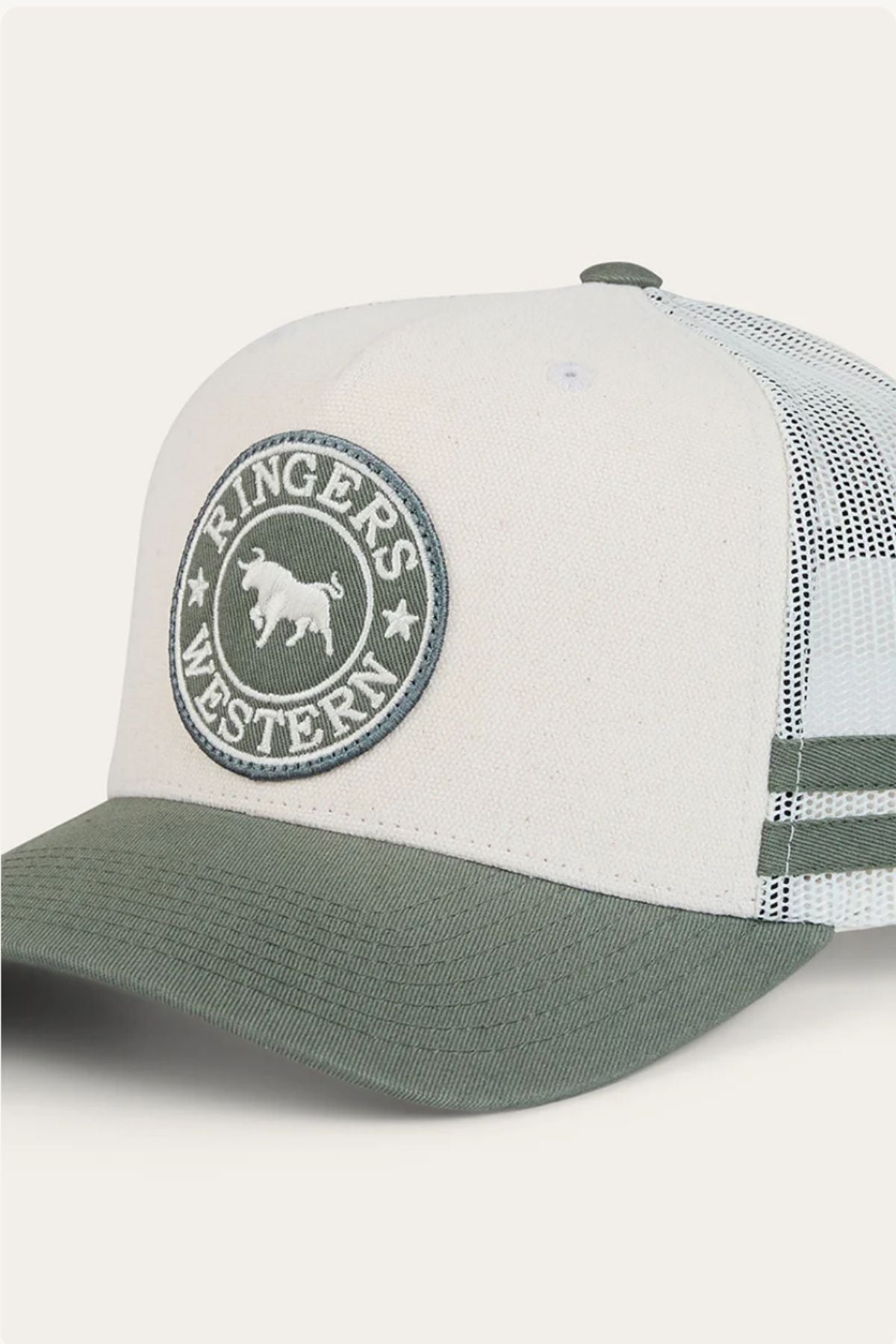 The Ringers Western McCoy Trucker Cap features a white cotton twill front, green bill, mesh back, and a circular patch with "Ringers Western" and a bull logo.