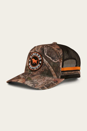 The Ringers Western McCoy Trucker Cap features a camo-patterned cotton twill front, black mesh back, and an orange and black "Ringers Western" bull logo. It also has an orange and black stripe on the side for added detail.