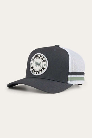 The Ringers Western McCoy Trucker Cap is a dark-colored baseball cap featuring a white mesh back and an adjustable snap closure. On the front, there's a round patch with an image of a bull, surrounded by the embroidered text "Ringers Western." This cotton twill trucker cap also includes two black stripes on the side mesh.