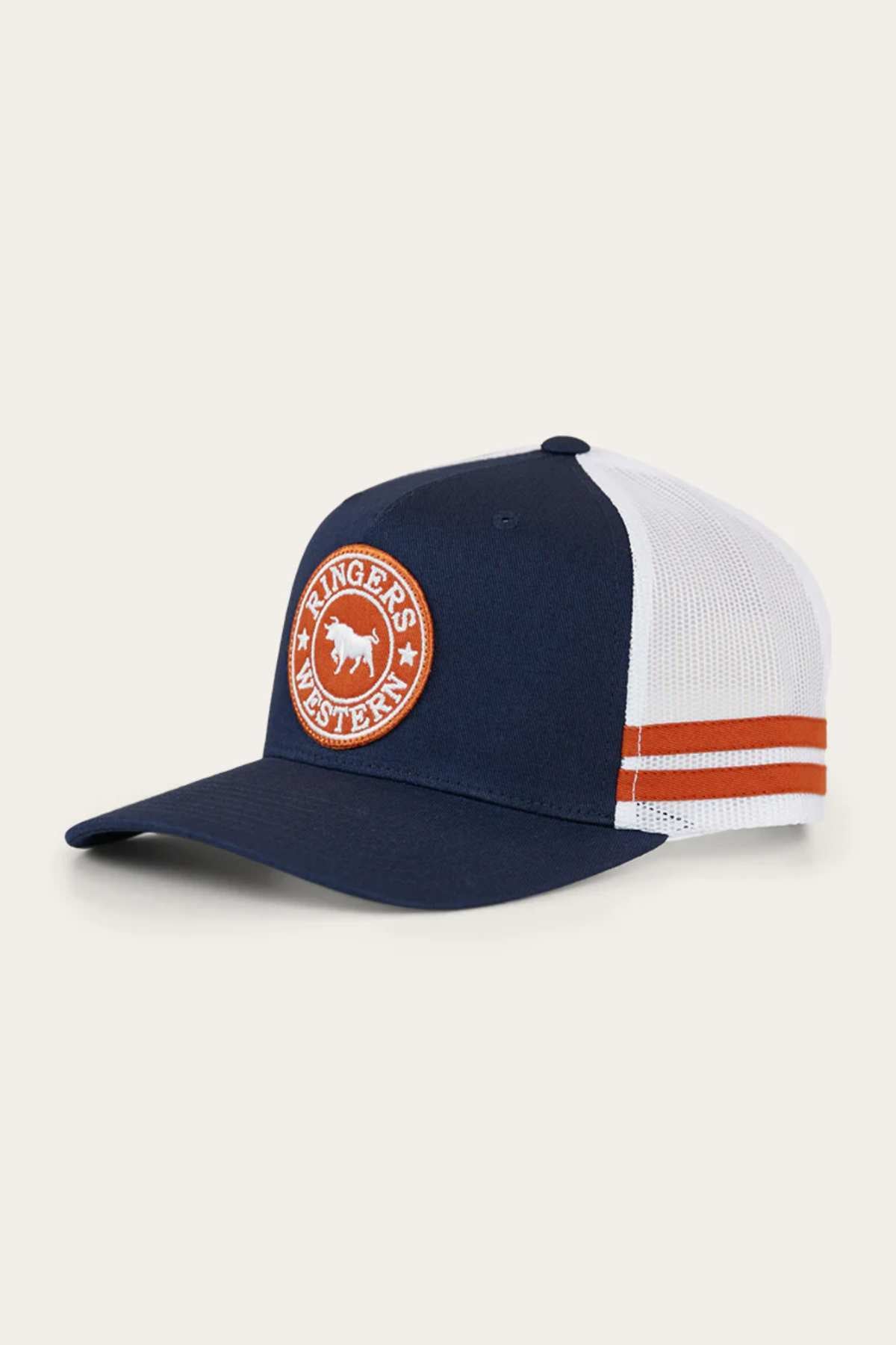 The Ringers Western McCoy Trucker Cap features a dark blue and white cotton twill design with a white mesh back. It has an orange and white circular emblem with a bull and the text "Ringers Western" on the front, as well as two orange stripes on the side.
