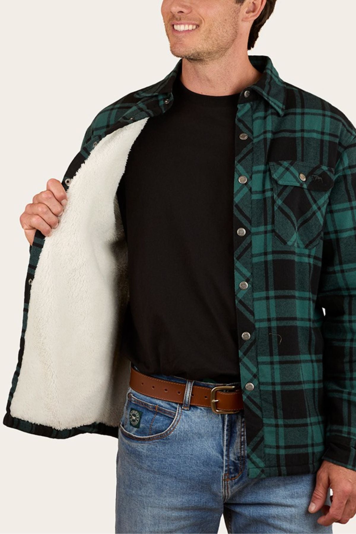 A man smiles while showing the white, fuzzy lining of his Ringers Western Sawyer Flannel Shirt, worn over a black t-shirt and blue jeans. Only his upper body is visible.