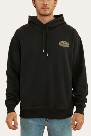 A man wearing a Ringers Western Servo Hoodie in black, featuring a small "Ringers" logo on the left chest, stands facing forward. The brushed fleece fabric and oversized fit offer both comfort and style, complementing his light blue jeans perfectly.