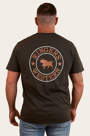 A man wears the Ringers Western Signature Bull Loose Fit T-Shirt made from 100% cotton, featuring a circular bull and stars design on the back, paired with light blue jeans while standing with arms relaxed.