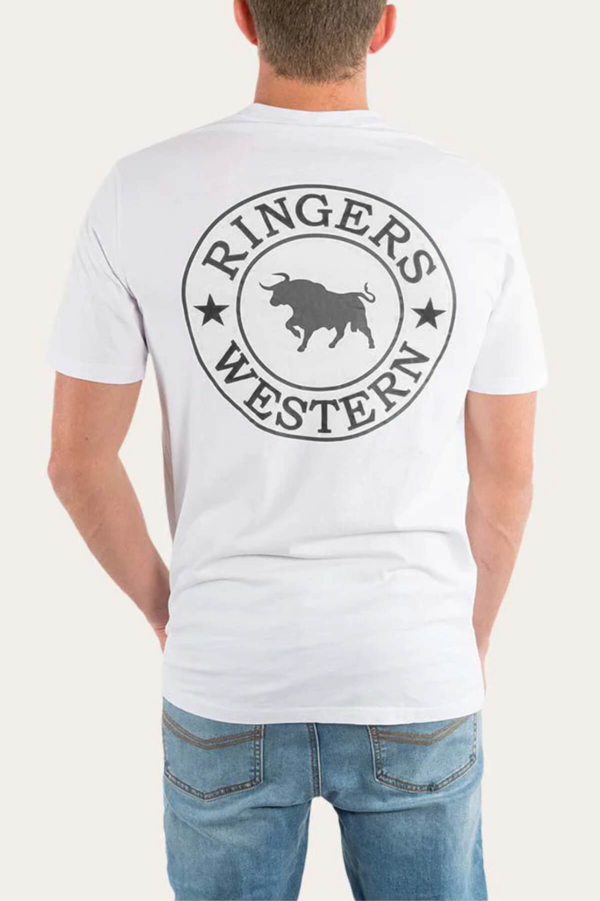 A man is facing away, wearing the Ringers Western Signature Bull Loose Fit T-Shirt in white, crafted from 100% cotton jersey. It features a circular "Ringers Western" bull logo on the back and is paired with light blue jeans.