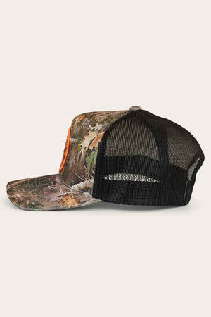 Side view of a Ringers Western Signature Bull Trucker Cap showcasing a black mesh back and orange logo. The cap's woodland pattern of leaves and twigs is set against a light cotton twill background.