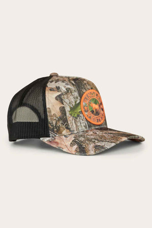 The Ringers Western Signature Bull Trucker Cap features a camouflage-patterned front and a black mesh back, adorned with an orange circular patch displaying a logo with text. Made from sturdy cotton twill, this cap is photographed on a light, neutral background, blending rugged style with comfort.