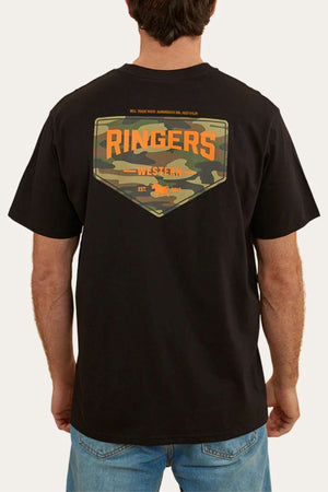 A person wearing the Ringers Western Squadron Loose Fit T-Shirt, made from pre-shrunk, 100% cotton jersey. The black t-shirt features a camo-patterned patch on the back with "Ringers Western" in large orange letters and smaller text that reads: "REAL TRADE MARK", "AUSTRALIAN 100% AUSTRALIAN", and "EST. 2012". The person