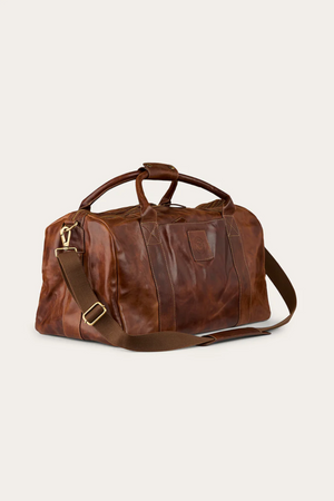The Ringers Western Toro Gino Overniter is a full grain leather overnight bag with double handles, gold-tone zipper, and an adjustable brown shoulder strapβideal for durable travel.