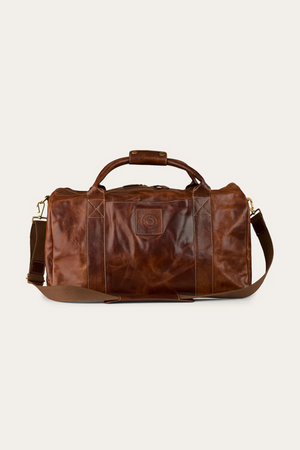 The Ringers Western Toro Gino Overniter is a full grain leather overnight bag with two handles, a shoulder strap, and a front stitched logo patchβideal as a durable travel companion. Displayed against a plain light background.