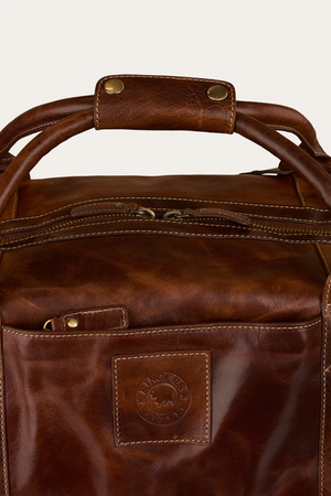 Close-up of a Ringers Western Toro Gino Overniter full grain leather bag with a sturdy handle, gold-tone hardware, front pocket, and an embossed patch showing the logo and animal graphic.