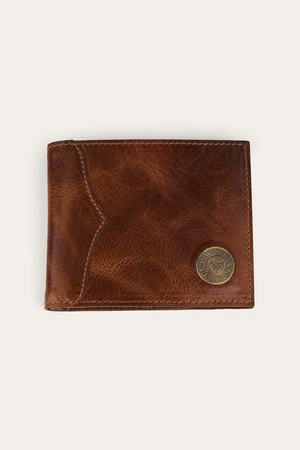 The Ringers Western Toro Midi Wallet is a slim, full-grain leather wallet featuring visible stitching and a round metallic emblem in the lower right corner, shown against a plain, light background.