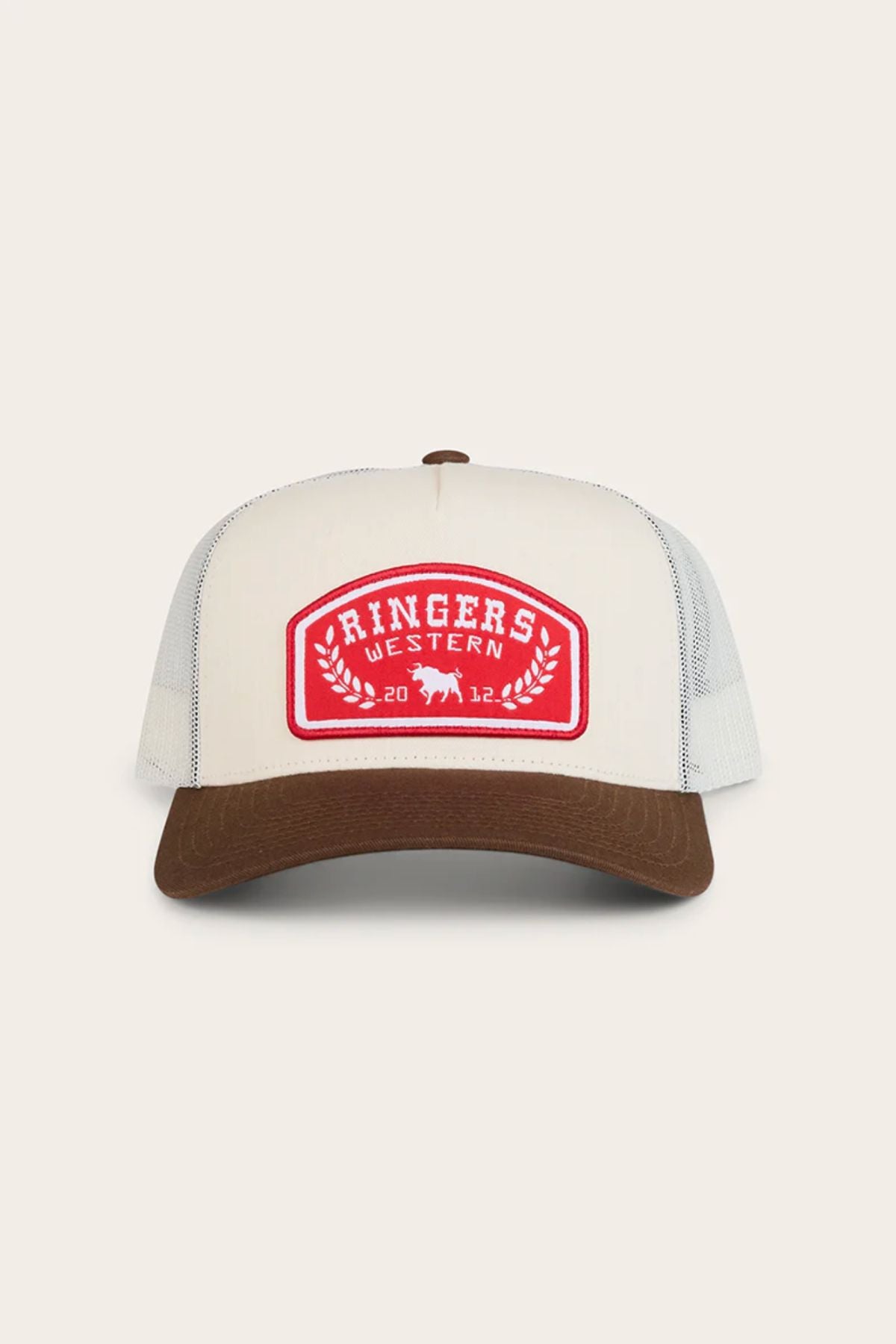 The Ringers Western Wheatbelt Trucker Cap is beige and brown with a red patch reading "RINGERS WESTERN 2012," two bulls, laurel branches, a brown curved brim, and a breathable mesh back for all-day comfort.