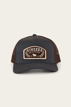The Ringers Western Wheatbelt Wool Trucker Cap has a brown and black design with an adjustable strap, featuring a "Ringers Western" front patch with a bold bull illustration, the numbers "20" and "12," and decorative leaves.
