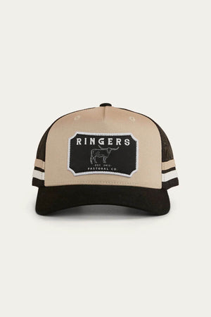 The Ringers Western Winston Trucker Cap is beige and black cotton twill with a black "RINGERS Pastoral Co." bull patch, two white side stripes, and a black mesh back.