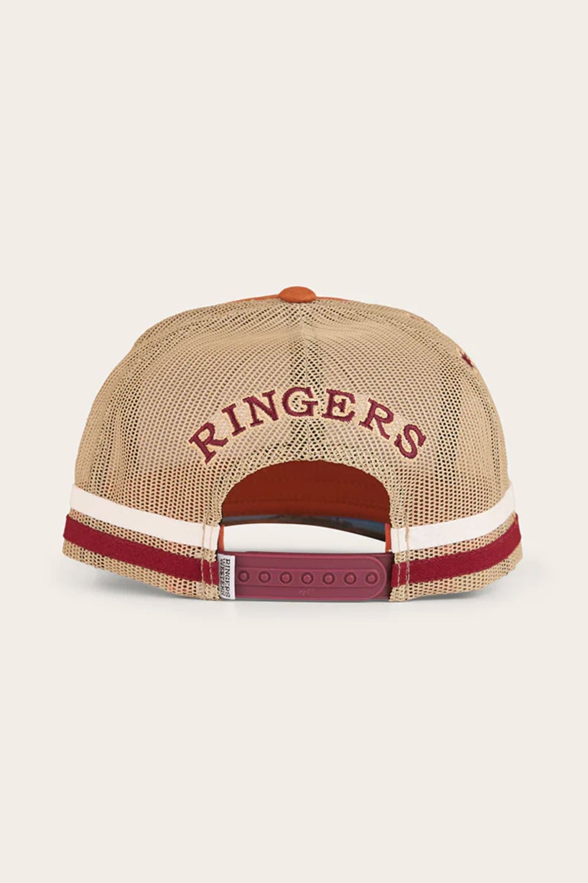 The Ringers Western Workhorse Trucker Cap in beige mesh is shown from the back, featuring "RINGERS" embroidered in red above the snap closure, with classic maroon and white stripes along the bottom edge.