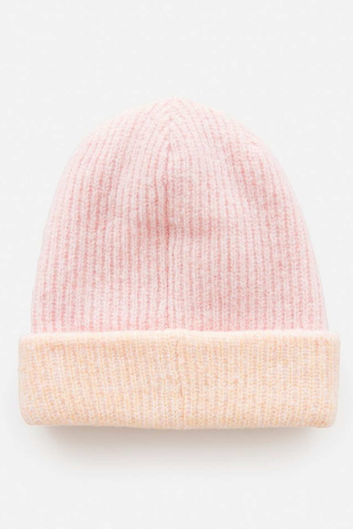 A light pink Rip Curl 2 Tone Reg Revo Beanie with a folded cuff rests against a plain white background. This tall beanie features a textured ribbed pattern, combining style and warmth.
