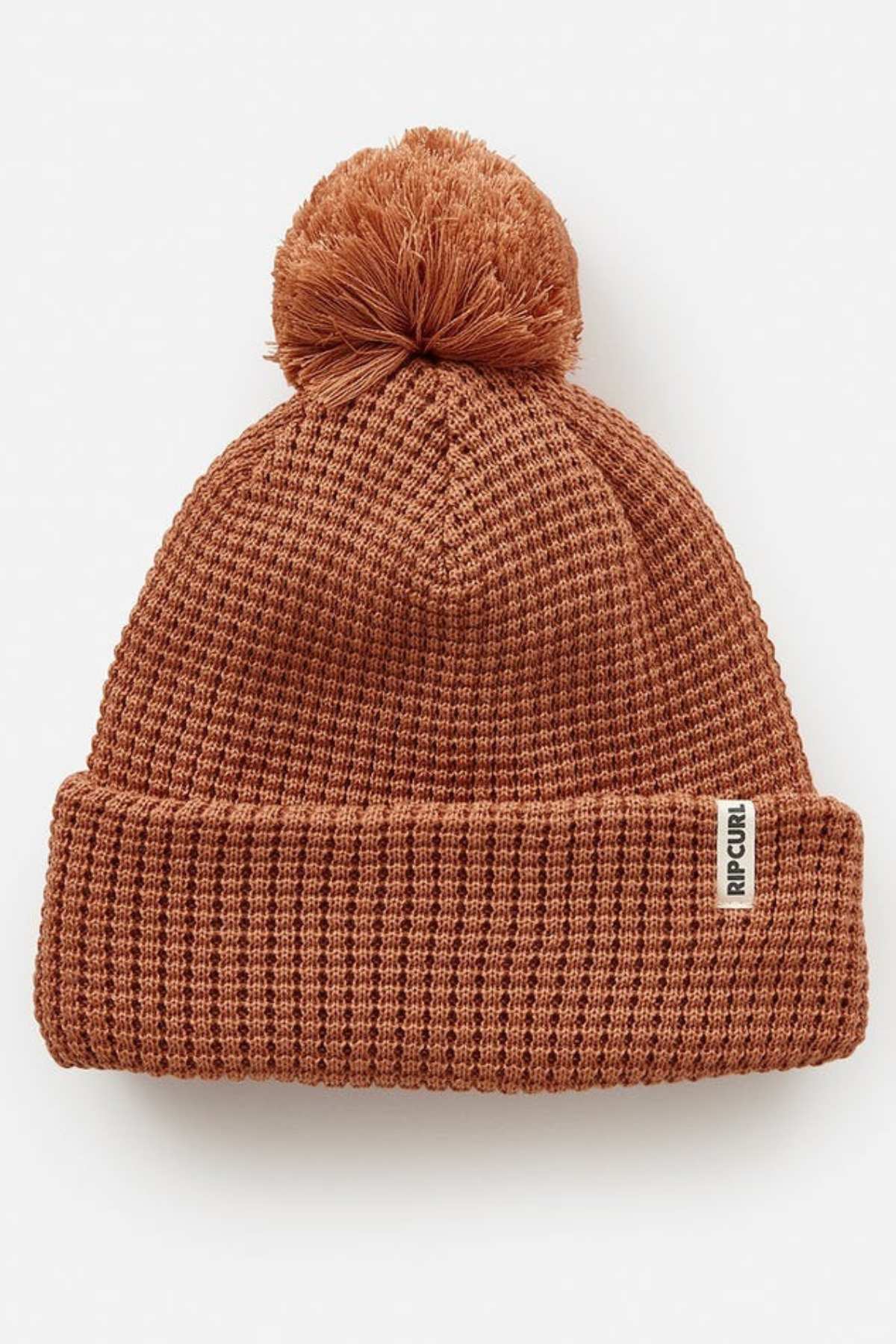 The Rip Curl Anoeta Reg Pom Pom Beanie is a cozy brown knit hat featuring a playful pom-pom, folded brim, and a small rectangular tag. Made from recycled polyester with teddy fur lining, it provides eco-friendly warmth.