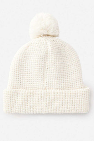 The Rip Curl Anoeta Reg Pom Pom Beanie showcases a white knit design with a folded brim, large pom-pom, and soft teddy fur lining, presented on a plain background.