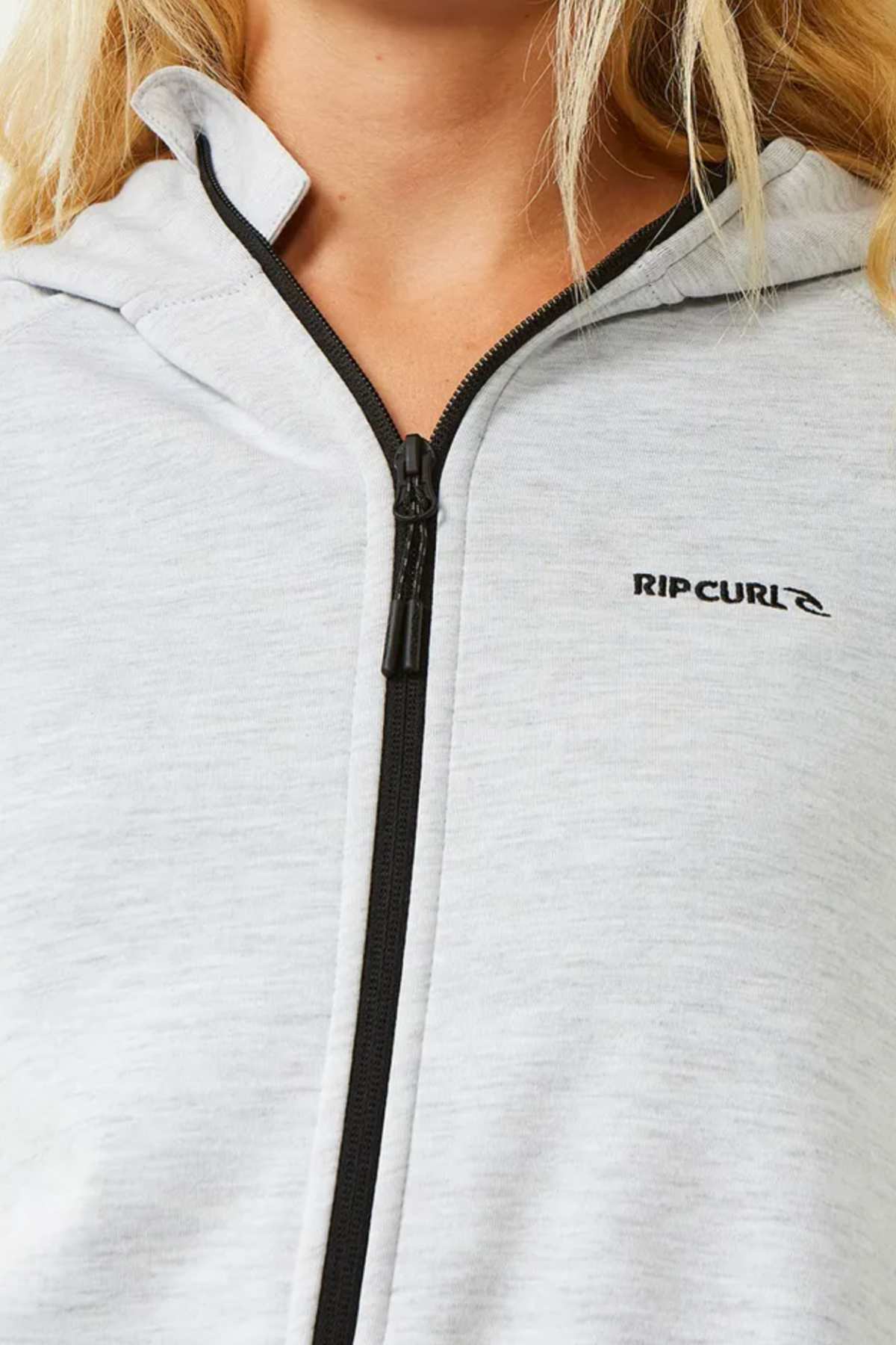 Close-up of a person wearing the Rip Curl Anti Series Flux III Zip hoodie in light gray, featuring bonded polar fleece, a black zipper, and the Rip Curl logo on the left chest. Only the lower face and upper torso are shown.