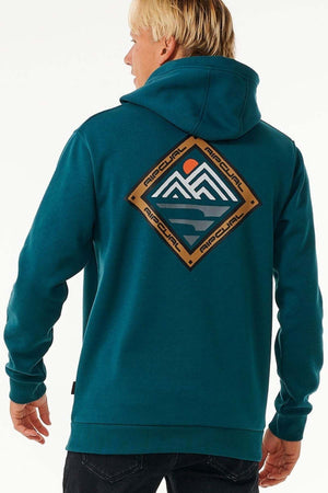 A person with blonde hair wears a teal Rip Curl Anti Series Journey Hood, featuring a mountain and sun graphic framed in a diamond with "AIRCOOL" repeated. This water-repellent hoodie includes thumb holes, and they are turned slightly to the side.