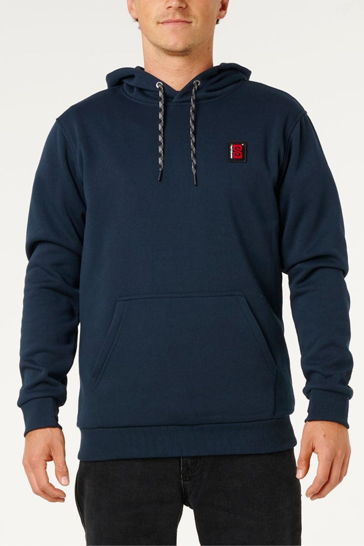 A man wearing a dark blue Rip Curl Anti Series Search Base Hood with water repellent fabric, polar fleece lining, front pocket, drawstrings, and a small red and black patch on the left chest stands facing forward.
