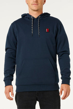 A man wearing a dark blue Rip Curl Anti Series Search Base Hood with water repellent fabric, polar fleece lining, front pocket, drawstrings, and a small red and black patch on the left chest stands facing forward.