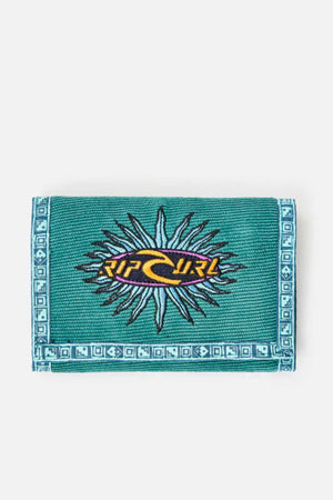 The Rip Curl Archive Cord Surf Wallet is designed in a green color with blue geometric border patterns and an embroidered central logo featuring a yellow wave against a black background with sun-like rays, all crafted from corduroy for a unique texture.