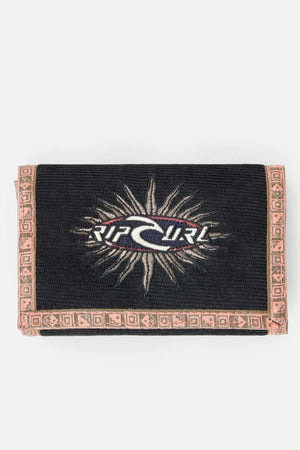 A black Rip Curl Archive Cord Surf Wallet features a white wave and sunburst logo on the front. The corduroy material is accented with a light beige woven border showcasing geometric patterns, and the brand name "Rip Curl" is prominently displayed in the center.