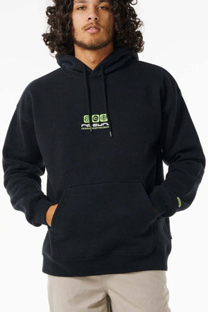 Wearing the Rip Curl Archive Ocean Tech Hood with neon green surf graphics and a front pocket, a person with curly hair stands, hands in the pocket, against a plain white background.