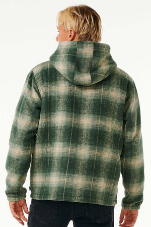 A person with blonde hair is seen from behind, wearing the Rip Curl Classic Surf Check Jacket with a sherpa-lined hood and dark jeans, set against a plain light background.