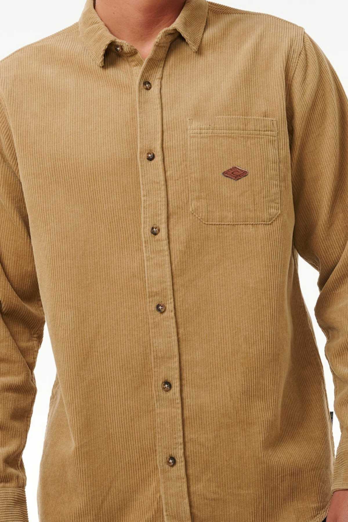 Wearing the stylish Rip Curl Classic Surf Cord Shirt, a beige corduroy button-up with dark buttons, a left chest pocket, and a small embroidered logo; the image is cropped at neck and waist to accentuate its trendy design.
