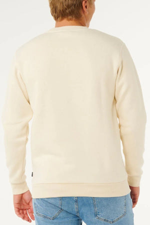 A person with short, light brown hair is pictured from the back in a cream Rip Curl Classic Surf Crew sweatshirt—an everyday piece with embroidered logo—paired with light blue jeans, set against a white background.