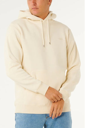 Someone wearing the Rip Curl Classic Surf Hood—a cream-colored hoodie with a front pocket and drawstrings—paired with light blue jeans, stands against a plain white background.