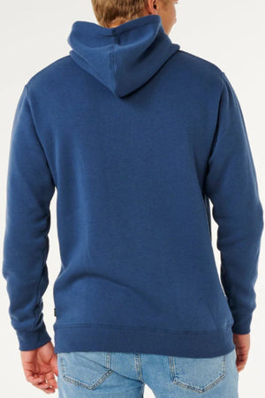 A person is seen from the back wearing a blue Rip Curl Classic Surf Hood and light blue jeans against a plain background.