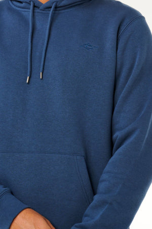 A person wearing a blue Rip Curl Classic Surf Hood with a small embroidered logo on the chest stands with arms crossed, showing only their torso and part of their arms.