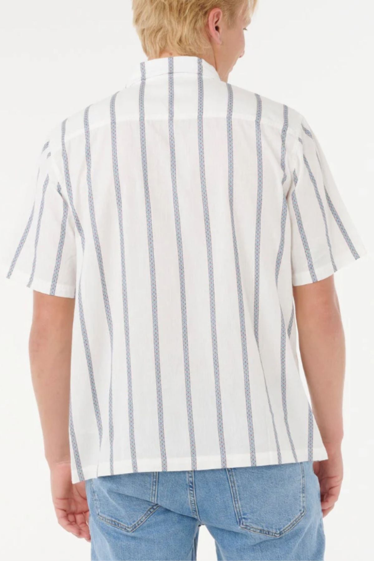 A person with short blond hair is seen from the back, wearing a Rip Curl Classic Surf Stripe Short Sleeve Shirt and light blue jeans, standing against a plain white background.