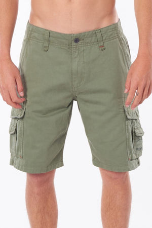 A person wearing Rip Curl Classic Surf Trail Cargo Short stands against a plain background, shown from the waist down. The olive green cargo shorts are knee-length, made of 100% cotton, and feature button closures and belt loops, offering a unique look with multiple pockets for practicality.