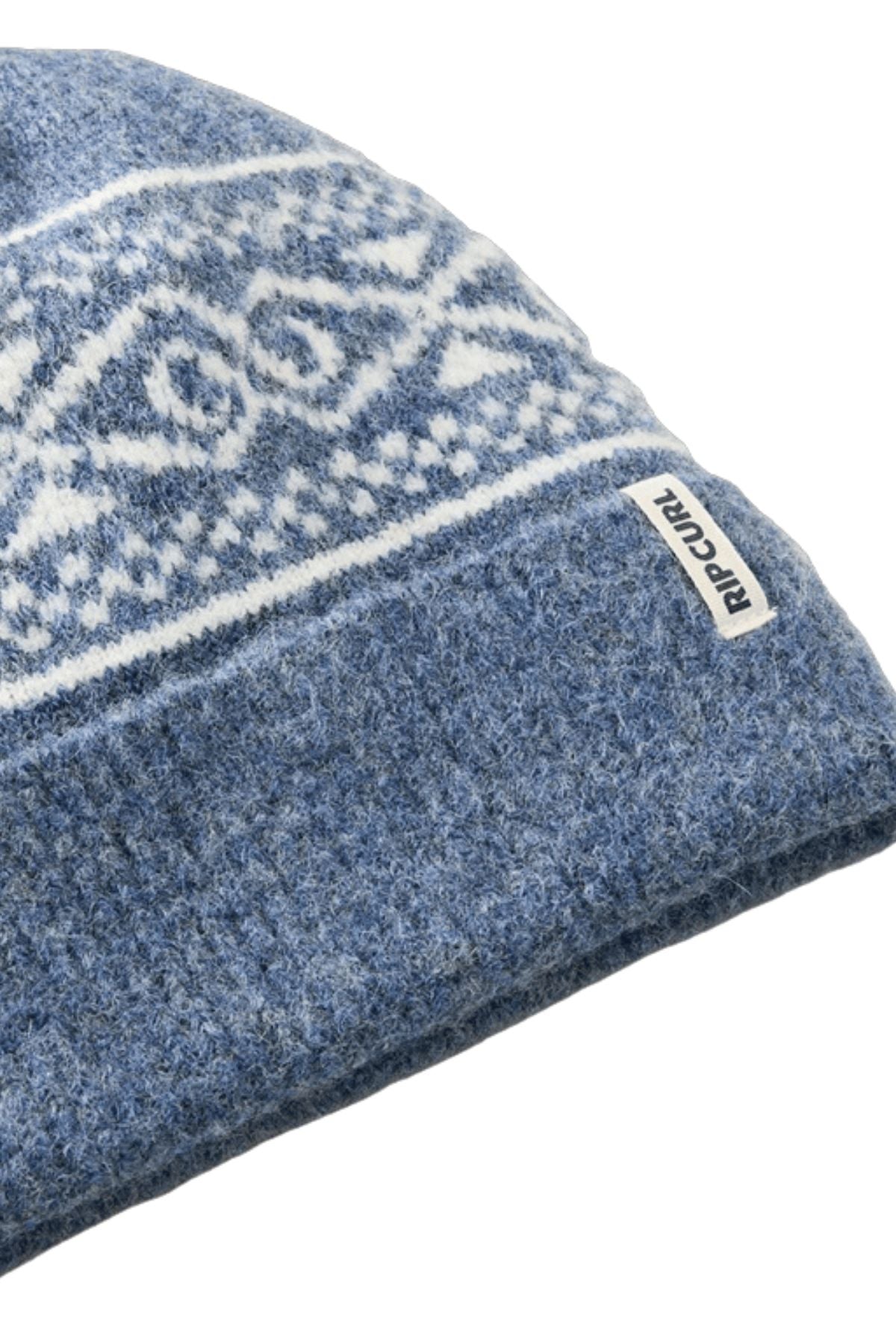 Close-up of the Rip Curl Cosmic Kiss Jacquard Beanie in blue, featuring white geometric patterns, a folded brim, and a small white "Rip Curl" tag on the brim—an eye-catching and stylish winter accessory.