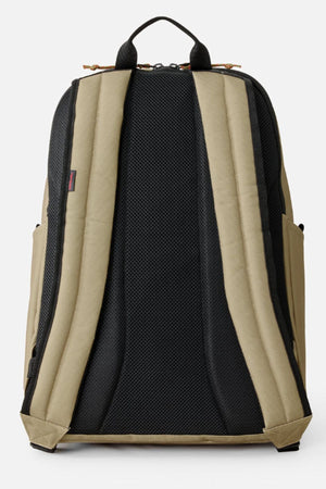 The Rip Curl Crusha 30L Search Backpack in khaki and black is shown from the back, featuring padded shoulder straps, a top handle, mesh padding for comfort, and visible side pockets and zippers.