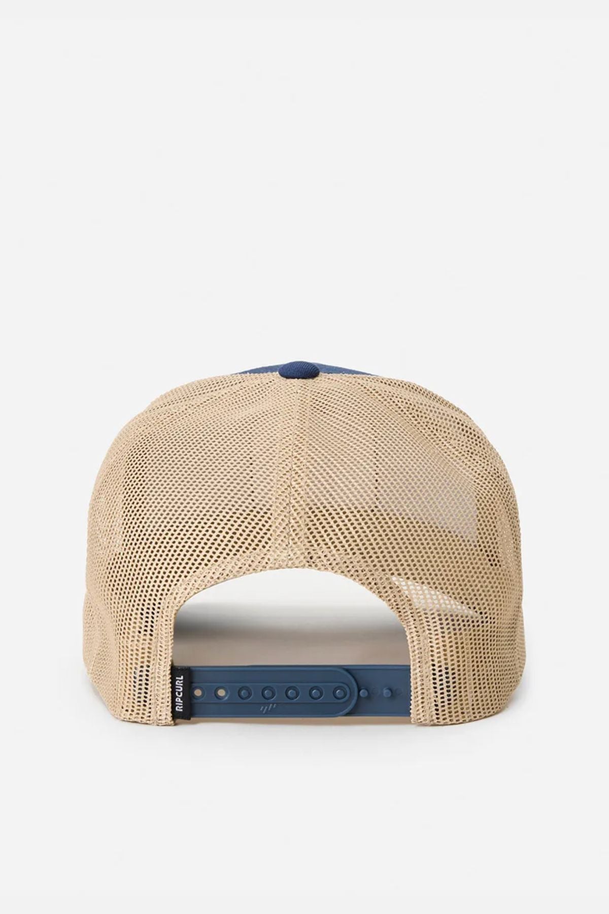 The Rip Curl Custom Curve Trucker is a beige cotton twill hat with a mesh back, blue adjustable snapback closure, curved peak, and a small black tag on the left side, shown from behind.