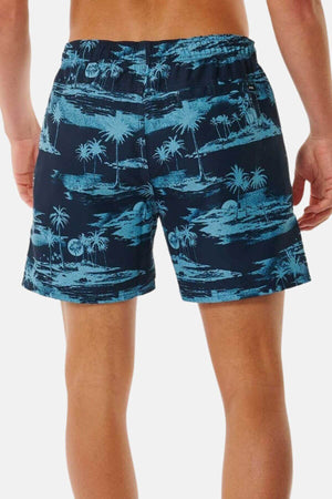 A person is standing with their back to the camera, wearing Rip Curl Dreamers Volley navy board shorts featuring a light blue tropical palm tree print.