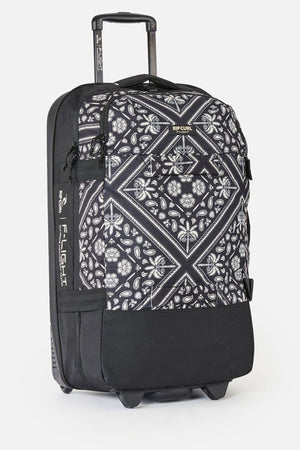 The Rip Curl F-Light Global 100L Bossa Nova is a check-in roller bag with a geometric and floral black-and-white design, extended handle, side pocket, AirTag sleeve, and Rip Curl branding on the top and side.