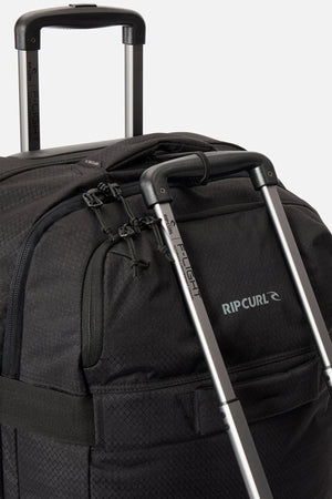 Close-up of two black Rip Curl F-Light Global 100L check-in suitcases with extended silver handles, zippers, and a visible brand logo on the fabric.