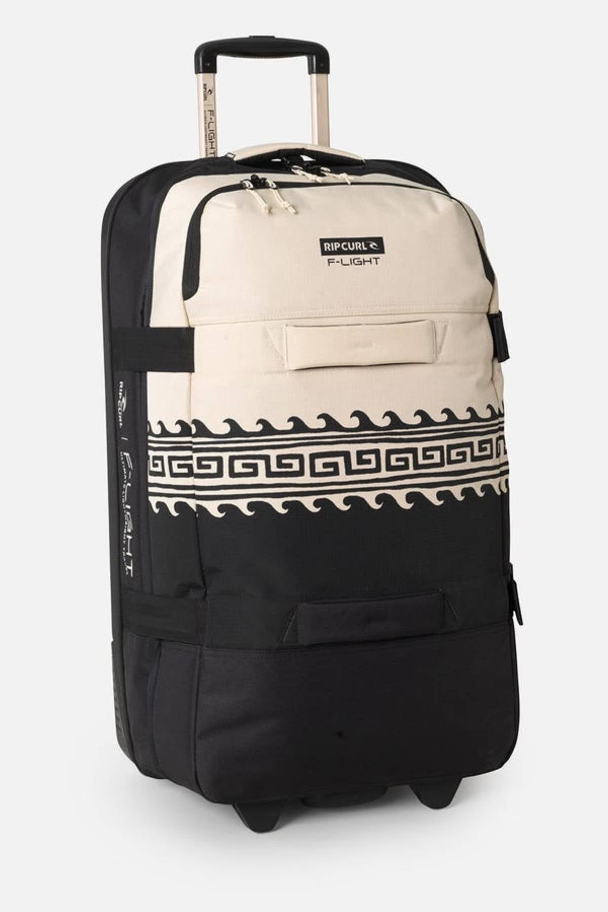 The Rip Curl F-Light Global 100L Soleil Travel Bag is a black and beige rolling suitcase with a Greek key pattern, made from recycled polyester. It has a telescopic handle, compression straps for efficient packing, and "Rip Curl F-Light" branding on the front.