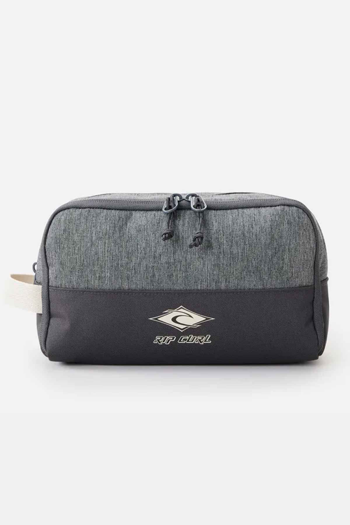 Introducing the Rip Curl Groom Classic Surf Toiletry Bagβan eco-friendly, rectangular design that combines a stylish two-tone look with a darker lower section and lighter gray upper. It proudly displays the Rip Curl logo on the front, has dual zipper pulls on top, and includes a small beige side handle for effortless portability.
