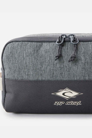 The Rip Curl Groom Classic Surf Toiletry Bag is an eco-friendly gray and black bag featuring a logo with a stylized "R" inside a diamond shape. It boasts a top zippered compartment with two pull tabs, offering a simple yet sporty design.