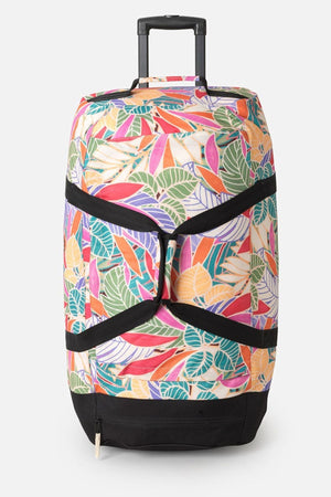 The Rip Curl Jupiter 80L Mixed Travel Bag is a vibrant, wheeled duffel with a tropical leaf pattern in pink, orange, green, and blue. Made of recycled polyester, it features black handles, a zippered compartment, sturdy black base, and telescopic handle for easy transport.