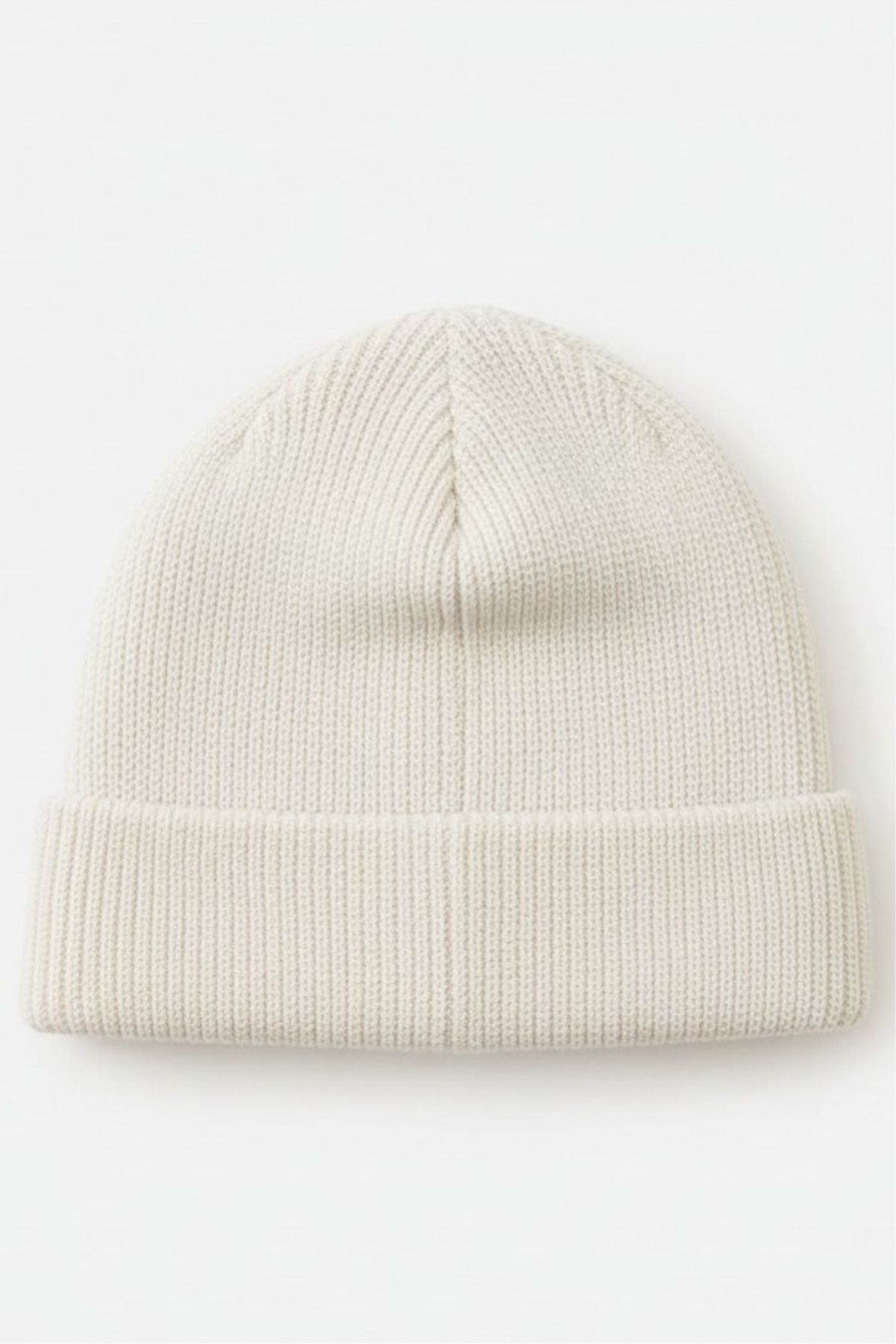 The Rip Curl Oceanic Reg Beanie is a plain, light beige ribbed knit beanie with a folded brim, shown flat on a white background—ideal cozy headwear for after water sports adventures.